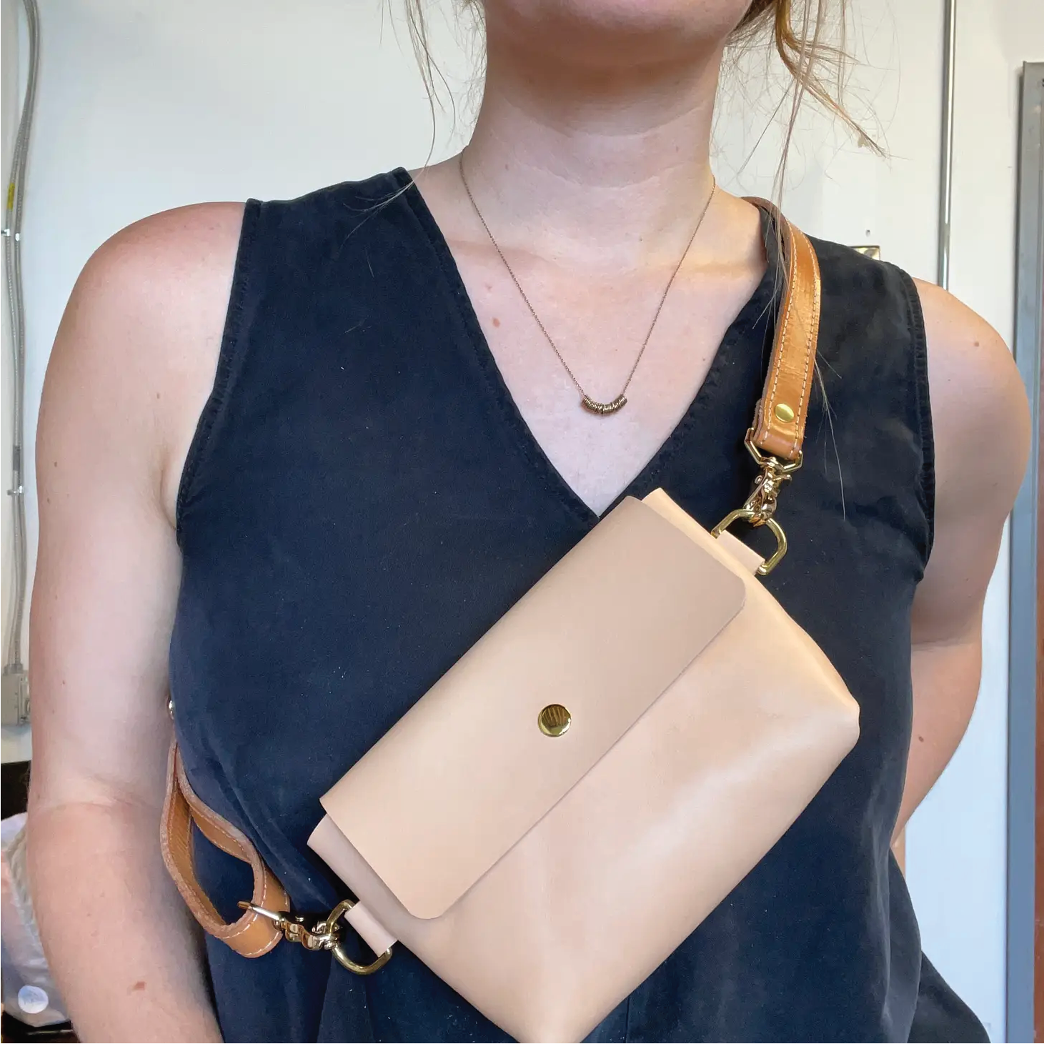 Natural leather color cross body bag slung over woman's body.